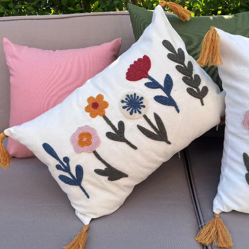 Decorative pillows with floral patterns on a gray sofa outdoors.