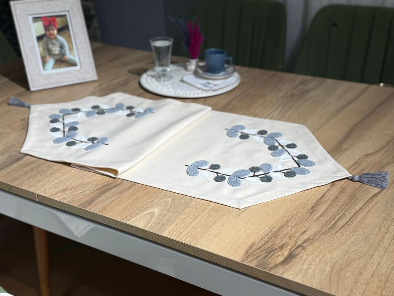 Embroidered leaf table runner in neutral fabric on wooden dining table with modern home decor