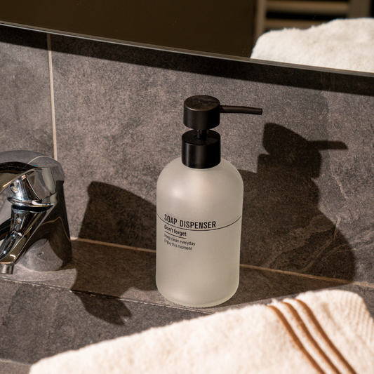 Frosted glass soap dispenser with black pump and modern text design