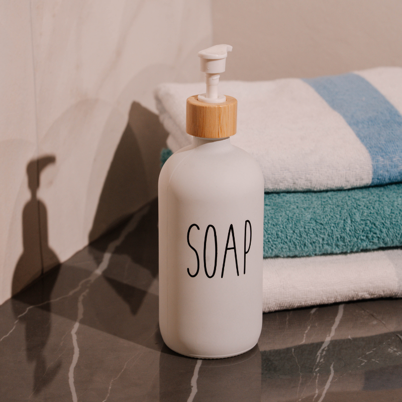 White soap dispenser with bamboo accent and minimalist text design