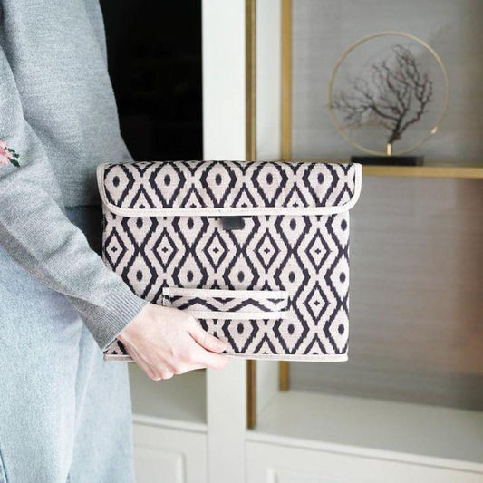 Beige and black diamond-patterned fabric storage box placed on a marble bathroom counter beside a sink.
