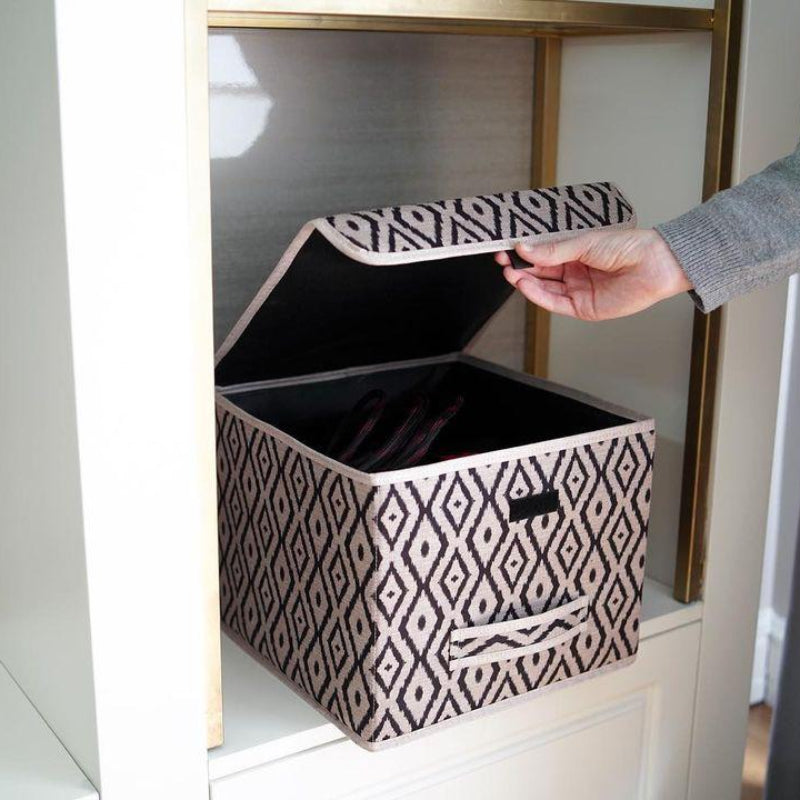Beige and black diamond-patterned fabric storage box placed on a marble bathroom counter beside a sink.