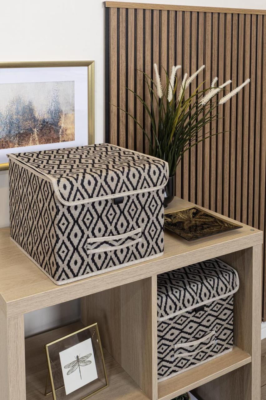 Beige and black diamond-patterned fabric storage box placed on a marble bathroom counter beside a sink.