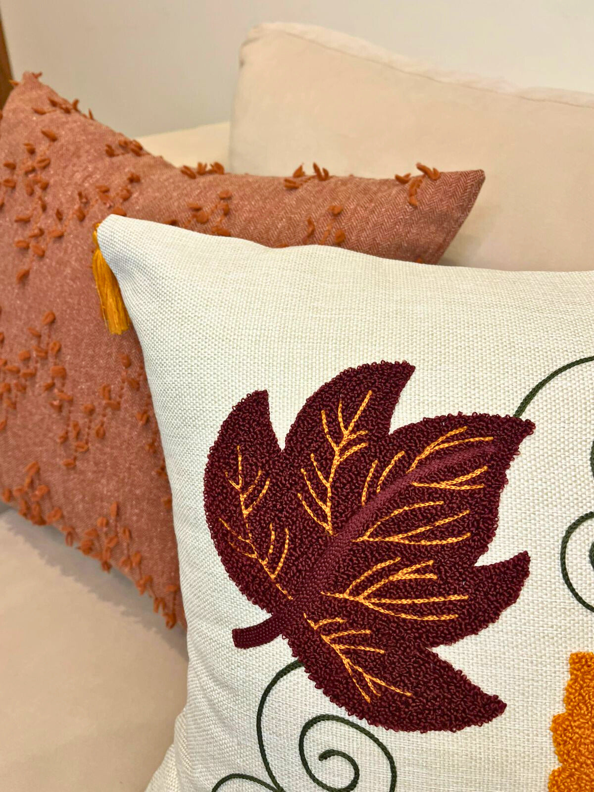 Square cushion cover with embroidered autumn leaves and tassels on beige sofa