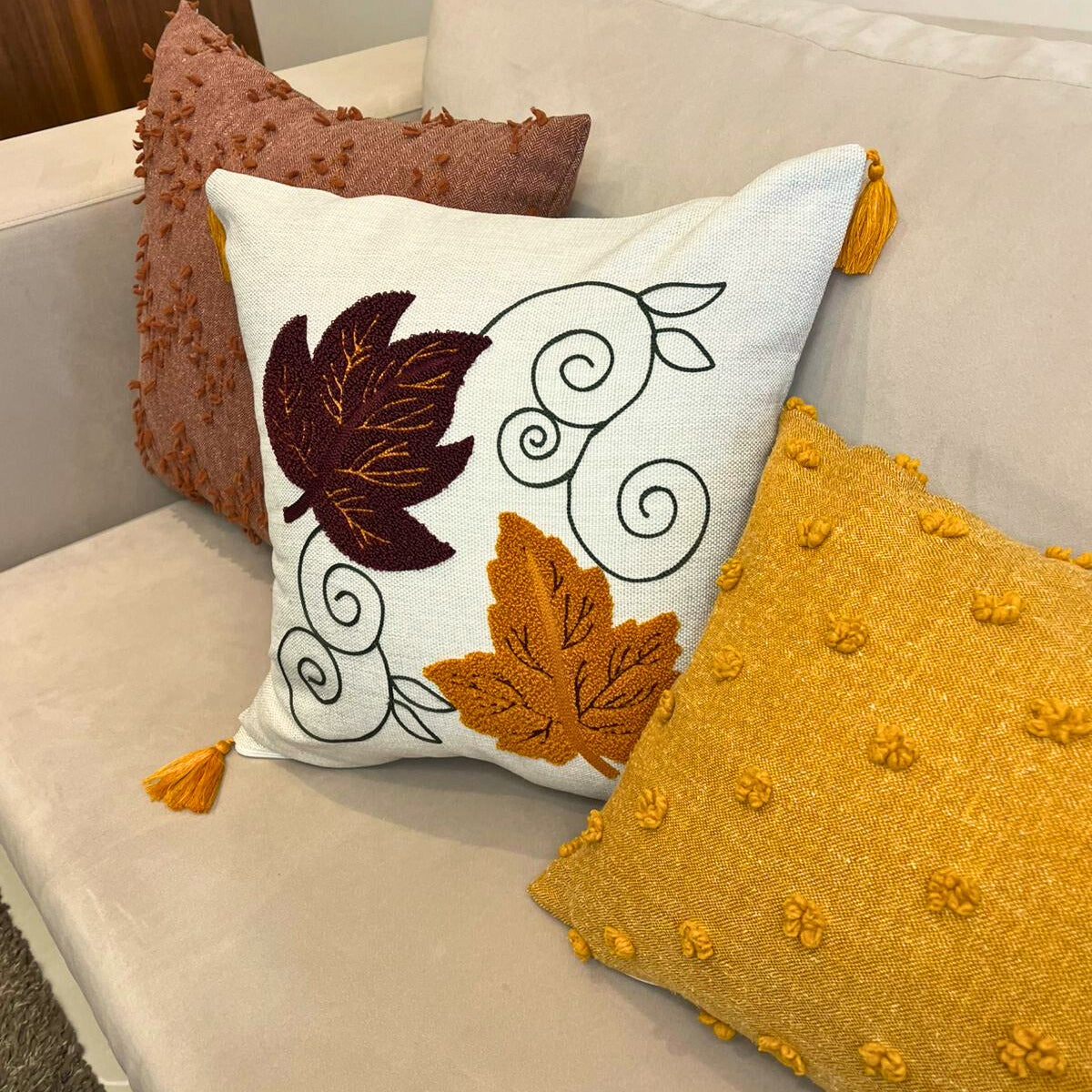 Square cushion cover with embroidered autumn leaves and tassels on beige sofa