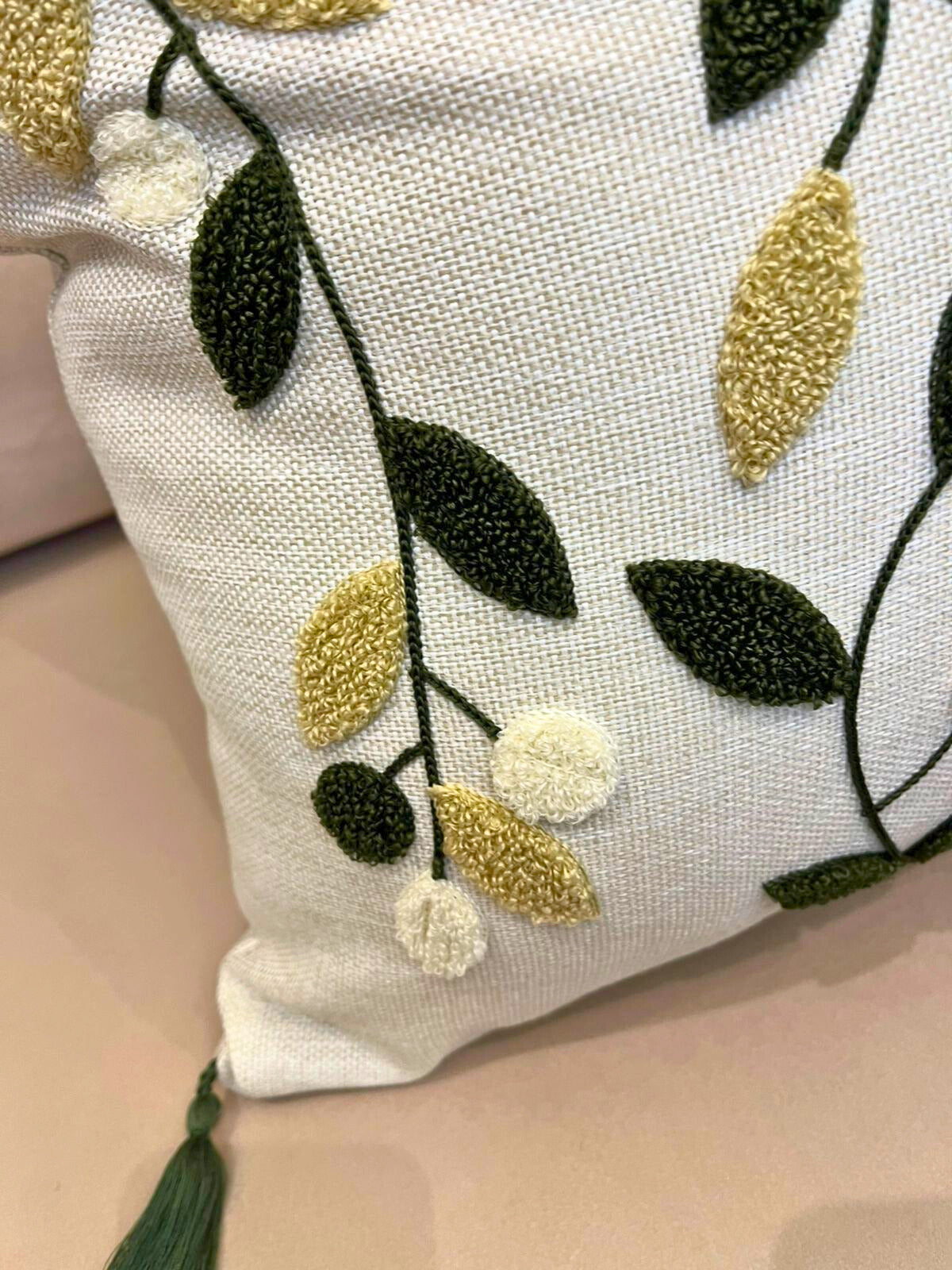 Square embroidered olive branch cushion cover with tassels on beige sofa