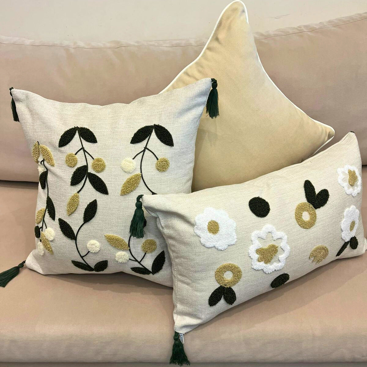 Square embroidered olive branch cushion cover with tassels on beige sofa