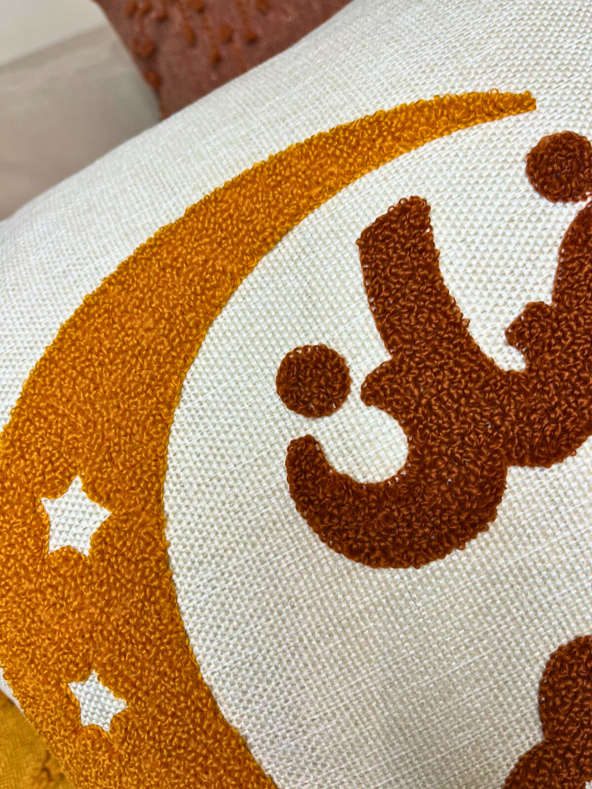 Square cushion cover with embroidered golden crescent moon and Arabic Ramadan Kareem text on sofa