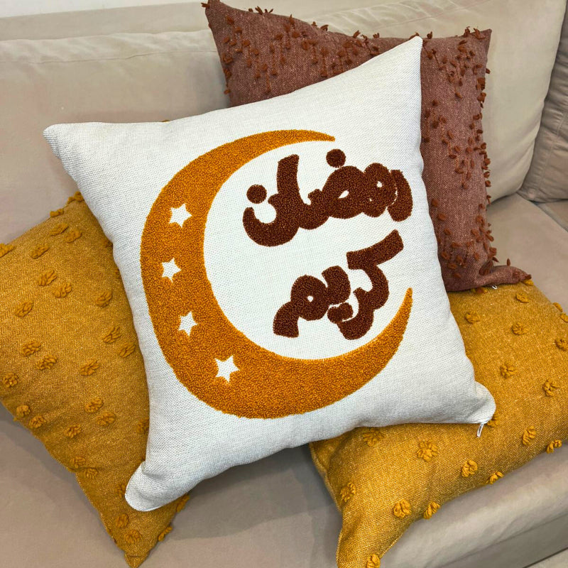 Square cushion cover with embroidered golden crescent moon and Arabic Ramadan Kareem text on sofa
