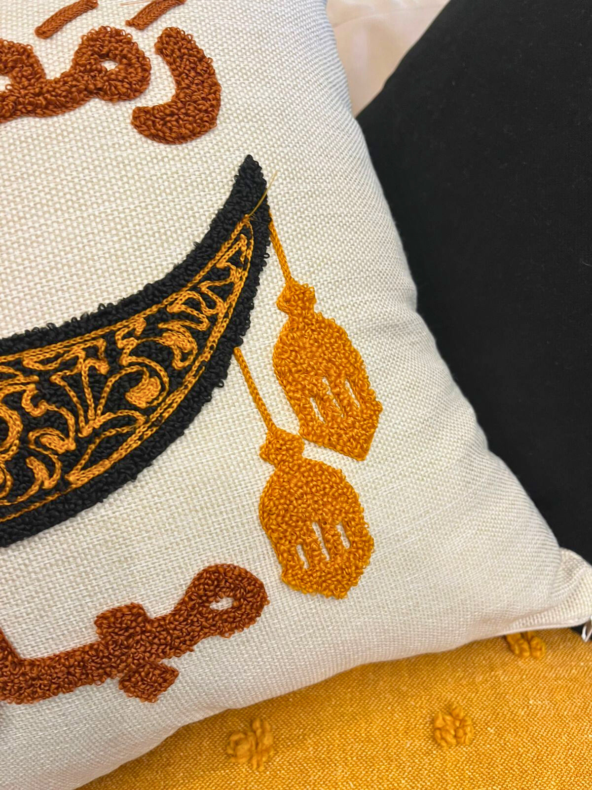 Square cushion cover with embroidered crescent moon and Arabic Ramadan Mubarak text on sofa