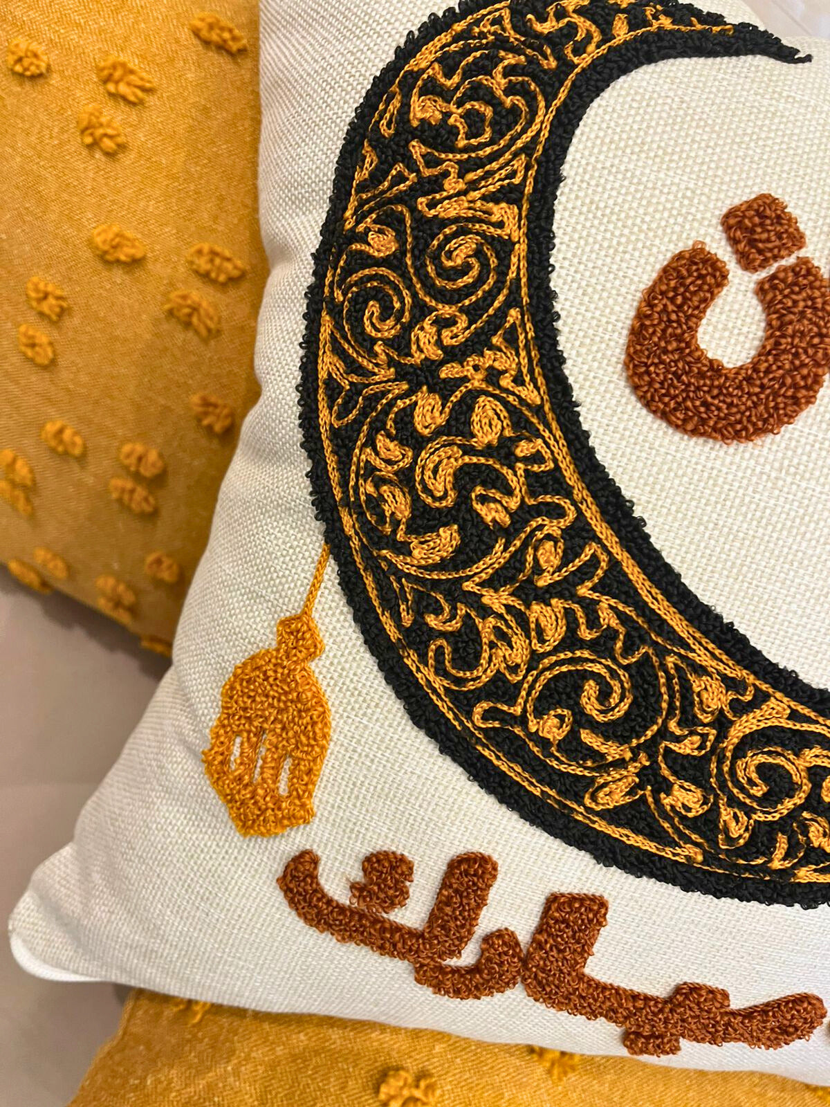 Square cushion cover with embroidered crescent moon and Arabic Ramadan Mubarak text on sofa