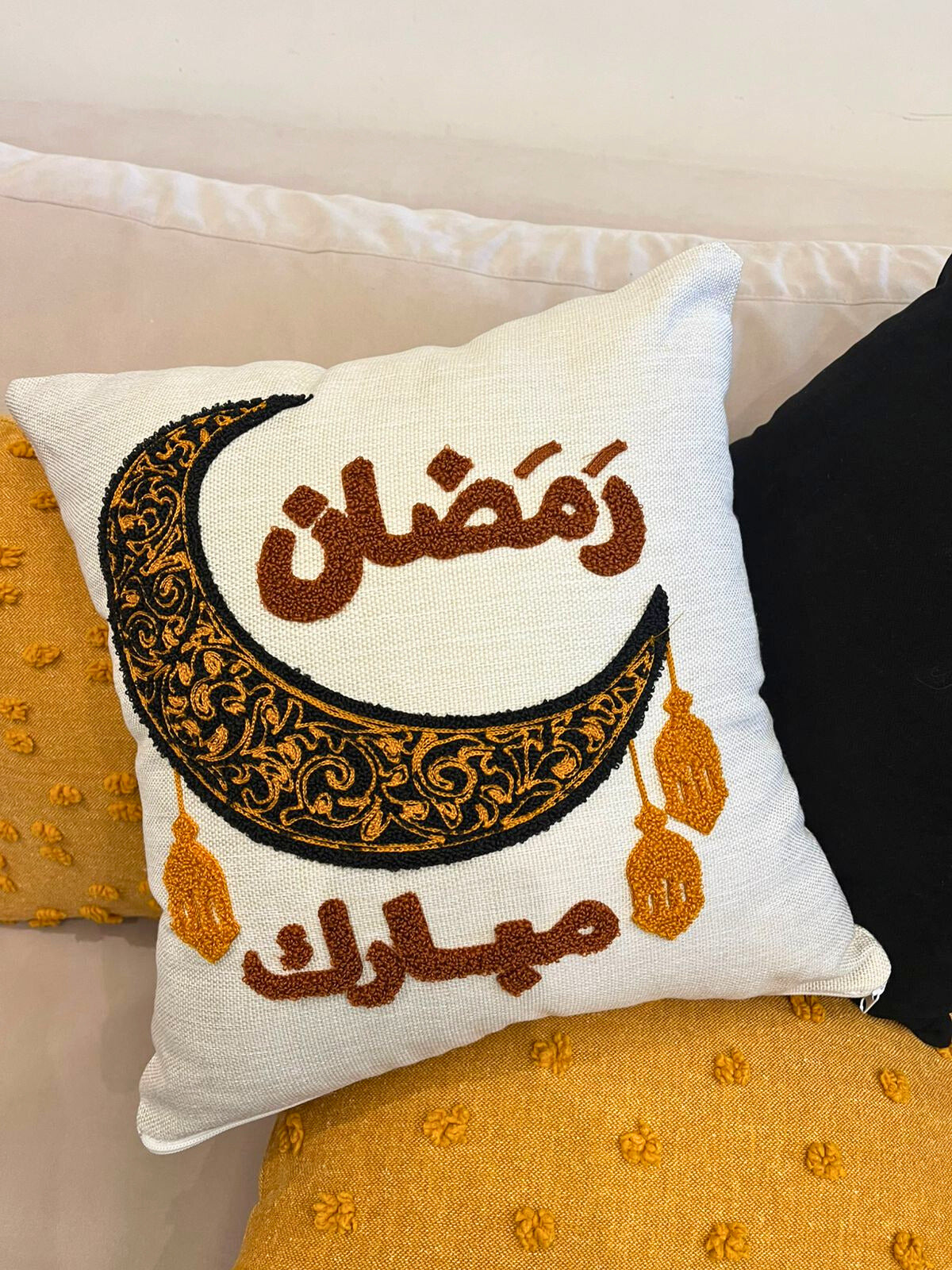 Square cushion cover with embroidered crescent moon and Arabic Ramadan Mubarak text on sofa