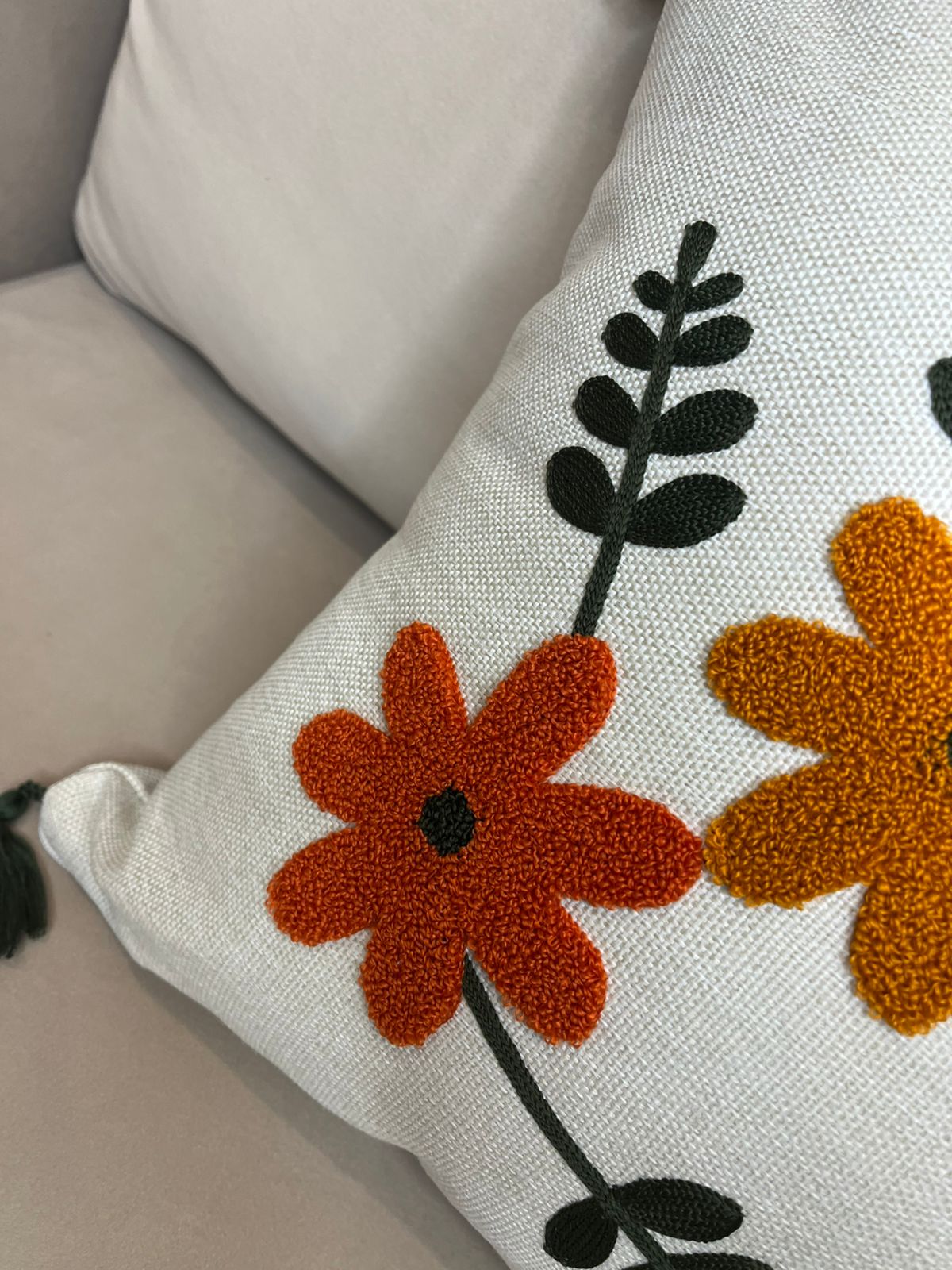 Multicolor embroidered floral cushion cover with tassels on beige sofa