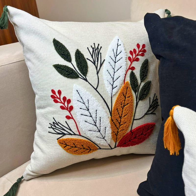Square embroidered cushion cover with multicolor leaf design and tassels on sofa