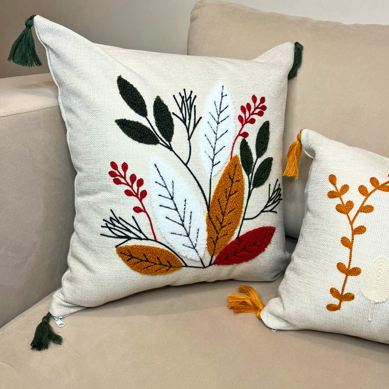 Square embroidered cushion cover with multicolor leaf design and tassels on sofa