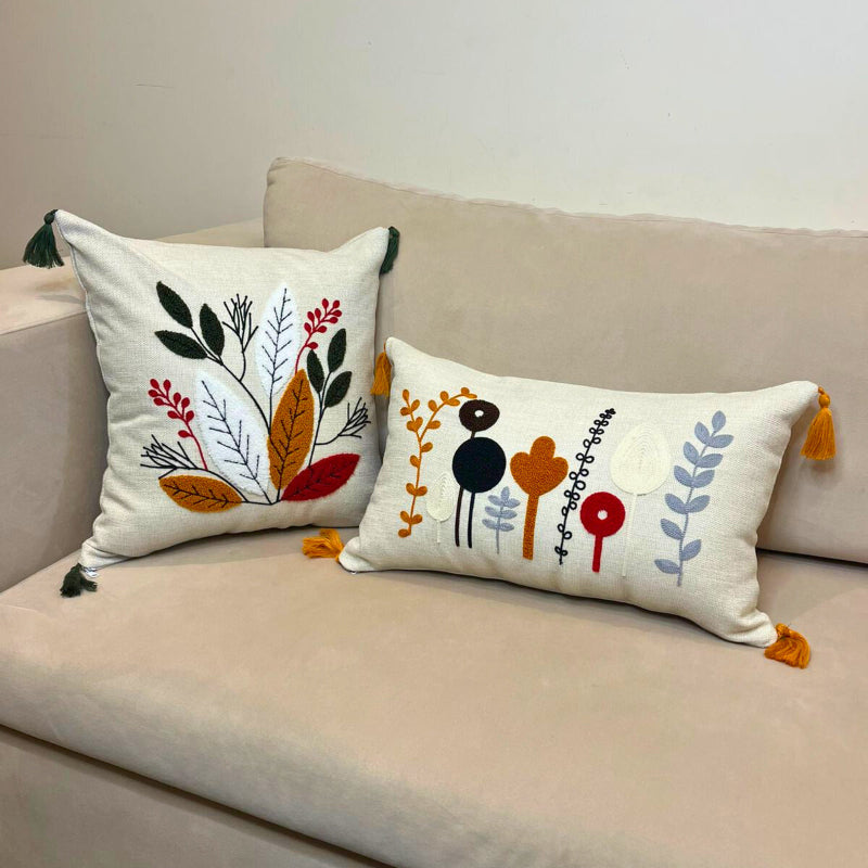 Square embroidered cushion cover with multicolor leaf design and tassels on sofa