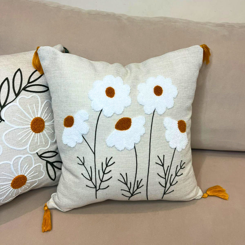 Square embroidered daisy cushion cover with tassels and white floral design on beige sofa