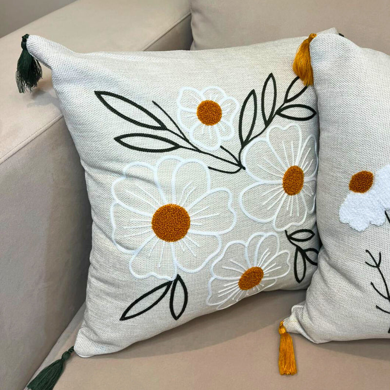 Square embroidered daisy cushion cover with tassels on beige sofa