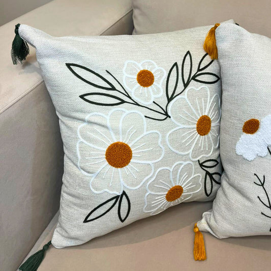 Square embroidered daisy cushion cover with tassels on beige sofa