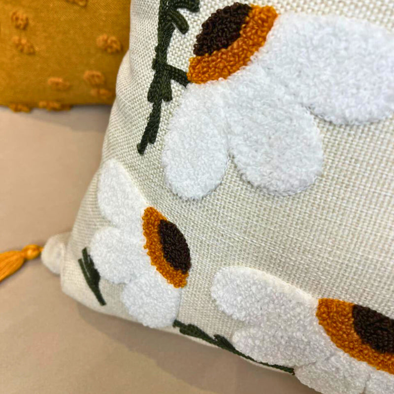 Square embroidered daisy cushion cover with tassels on beige sofa