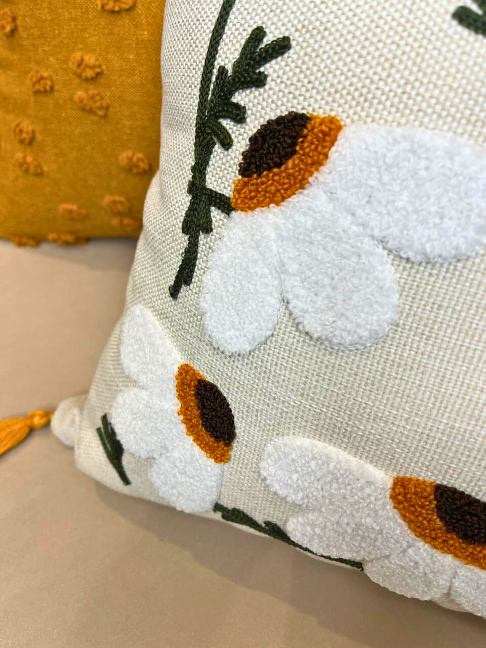 Rectangular embroidered daisy cushion cover with tassels on beige sofa