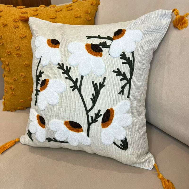 Square embroidered daisy cushion cover with tassels on beige sofa