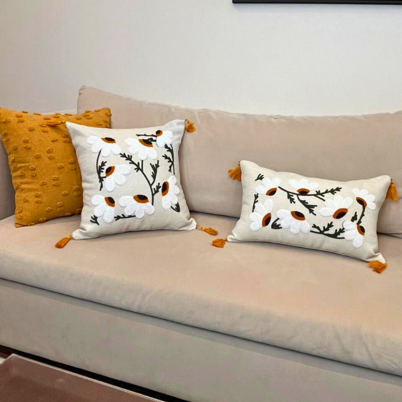 Rectangular embroidered daisy cushion cover with tassels on beige sofa