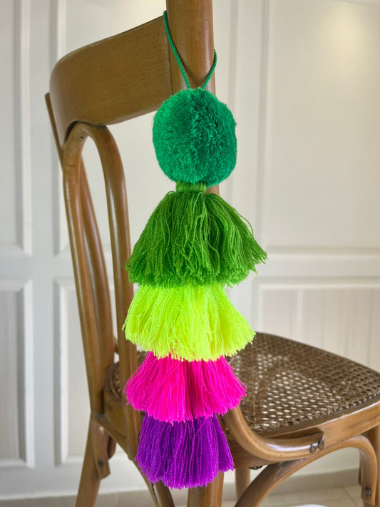 Handmade neon green pom pom tassel hanging decor with layered colorful yarn tassels displayed on wooden chair