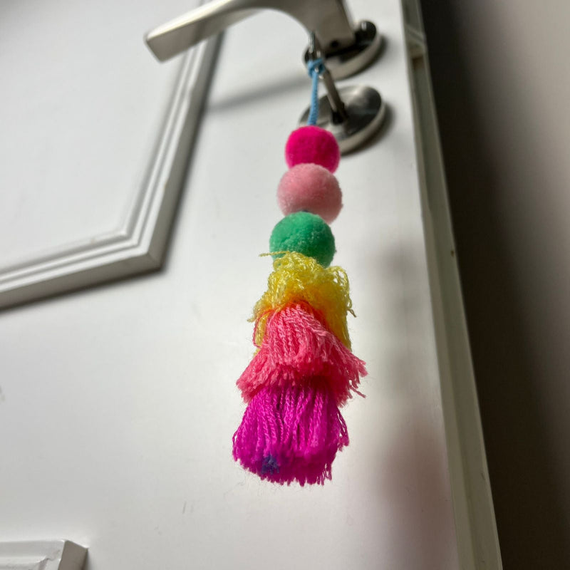 Colorful tassel keychain hanging on a door handle.
