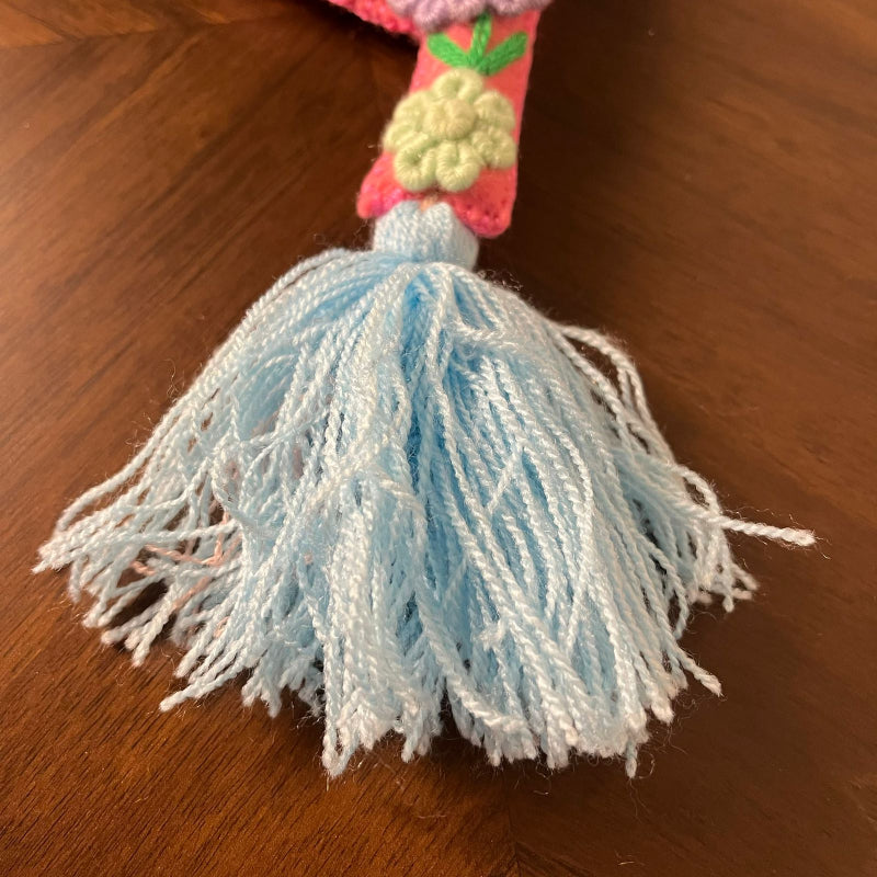 Handmade embroidered letter Y ornament with colorful floral stitching and blue tassel on wooden background