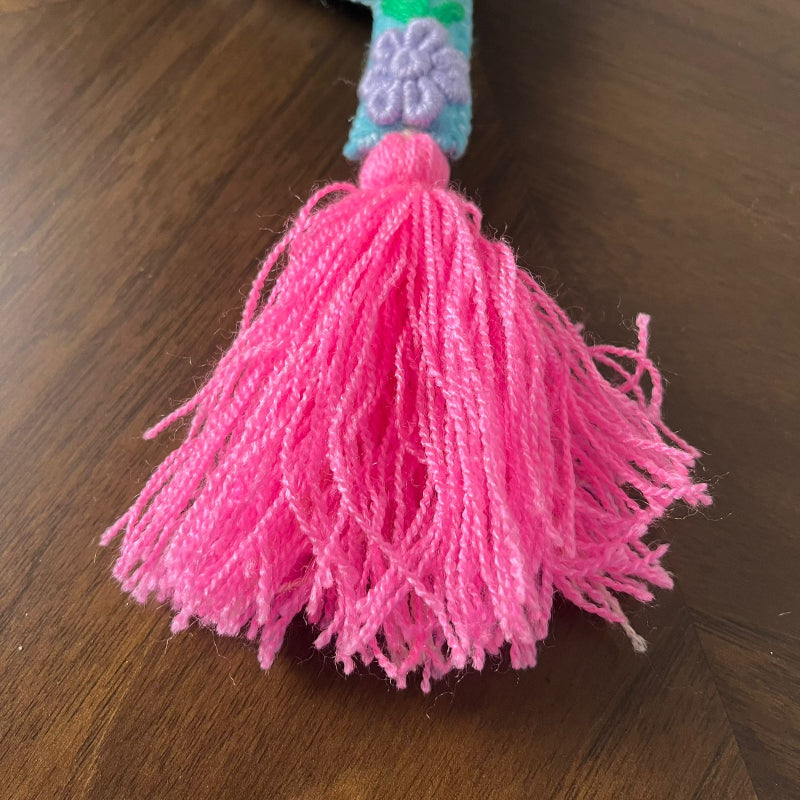 Handmade embroidered letter Y ornament with colorful floral stitching and bright pink tassel on wooden surface