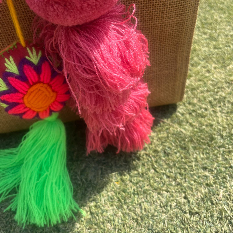 Pinky fluffy tassel keychain with soft pom pom placed on grass background