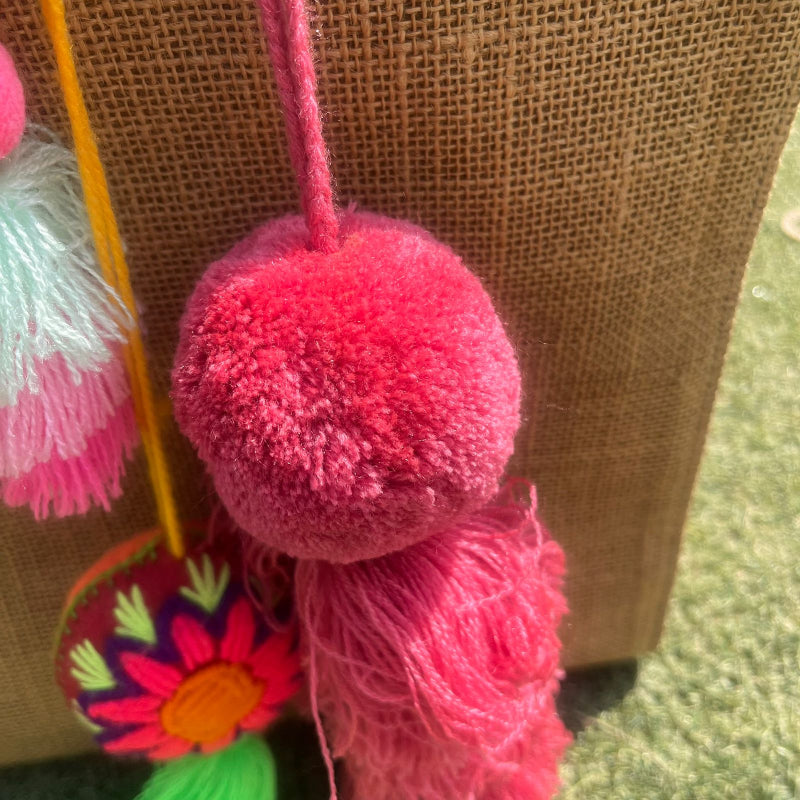 Pinky fluffy tassel keychain with soft pom pom placed on grass background