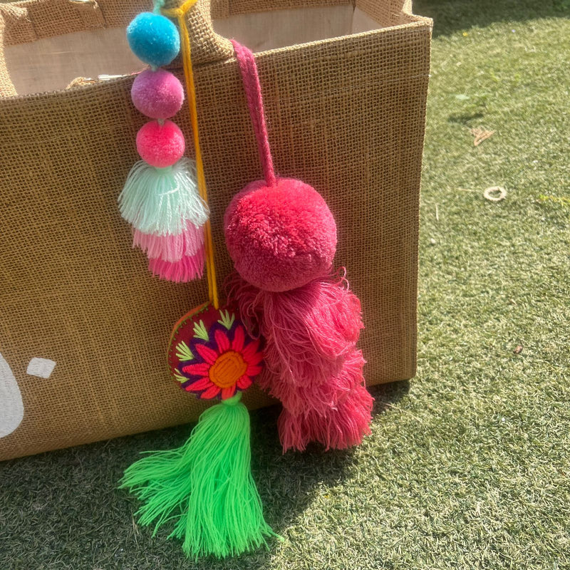 Pinky fluffy tassel keychain with soft pom pom placed on grass background