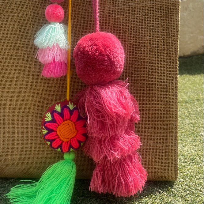 Pinky fluffy tassel keychain with soft pom pom placed on grass background