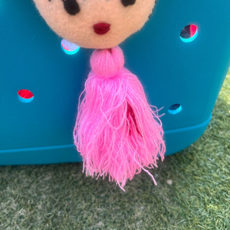 Handmade Frida-inspired doll charm with colorful pom-poms and soft pink tassel on teal bag