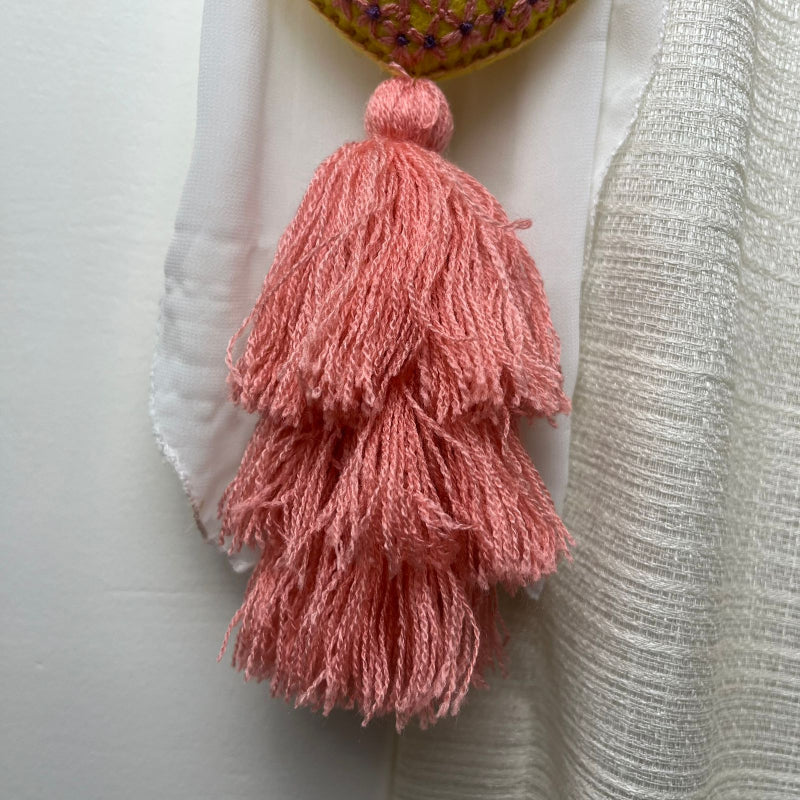 Handmade embroidered heart tassel with pink yarn fringe hanging on curtain
