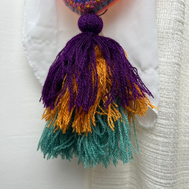 Handmade multicolor embroidered heart tassel with colorful floral embroidery and layered yarn fringe on curtain