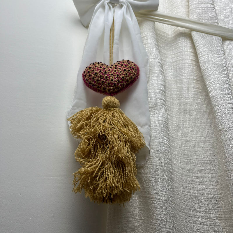 Handmade gold embroidered heart tassel with floral embroidery and gold yarn fringe on curtain