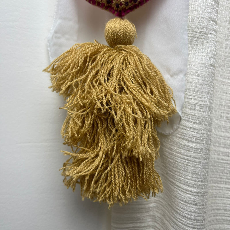 Handmade gold embroidered heart tassel with floral embroidery and gold yarn fringe on curtain