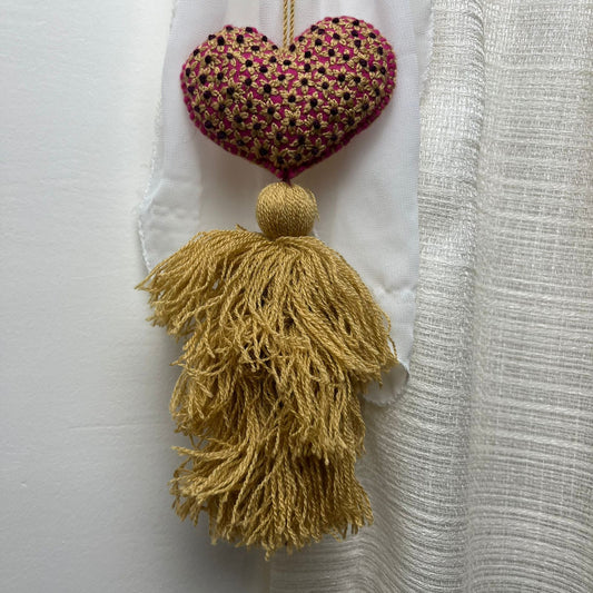 Handmade gold embroidered heart tassel with floral embroidery and gold yarn fringe on curtain