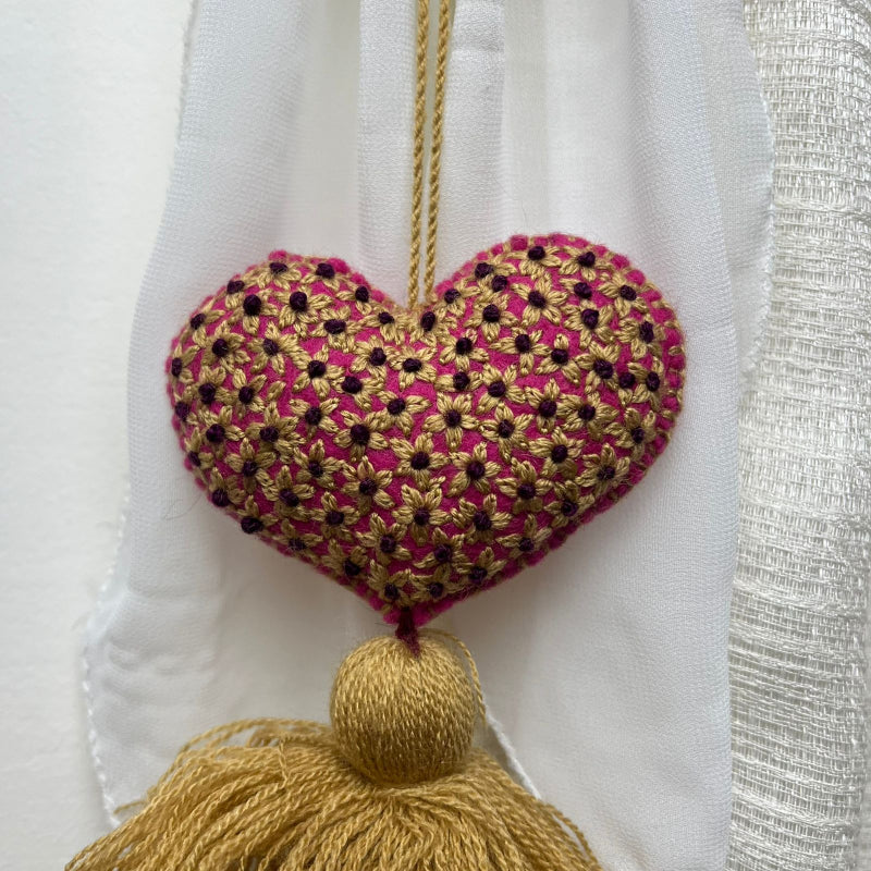 Handmade gold embroidered heart tassel with floral embroidery and gold yarn fringe on curtain