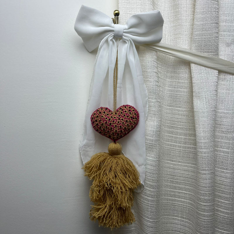 Handmade gold embroidered heart tassel with floral embroidery and gold yarn fringe on curtain