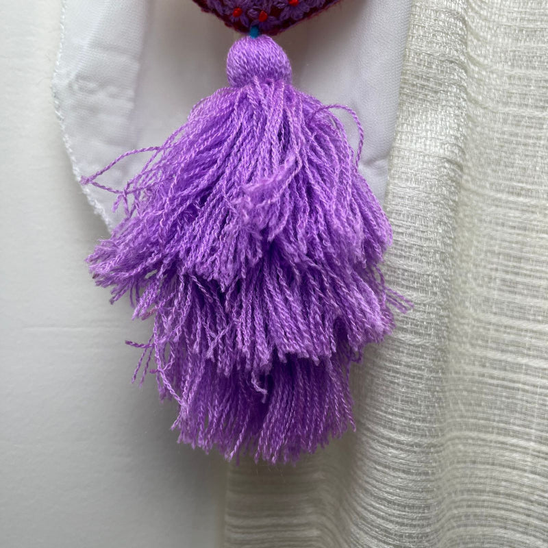Handmade purple embroidered heart tassel with red floral embroidery and purple yarn fringe on curtain