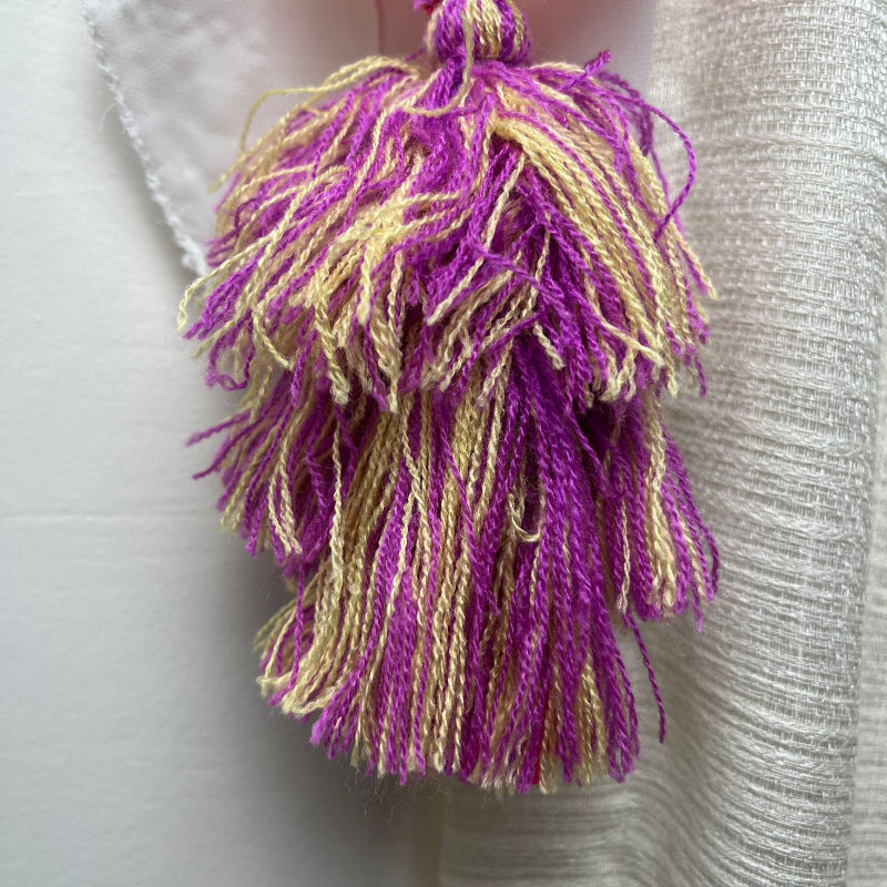 Handmade olive embroidered heart tassel with purple and yellow floral embroidery and two-tone yarn fringe on curtain