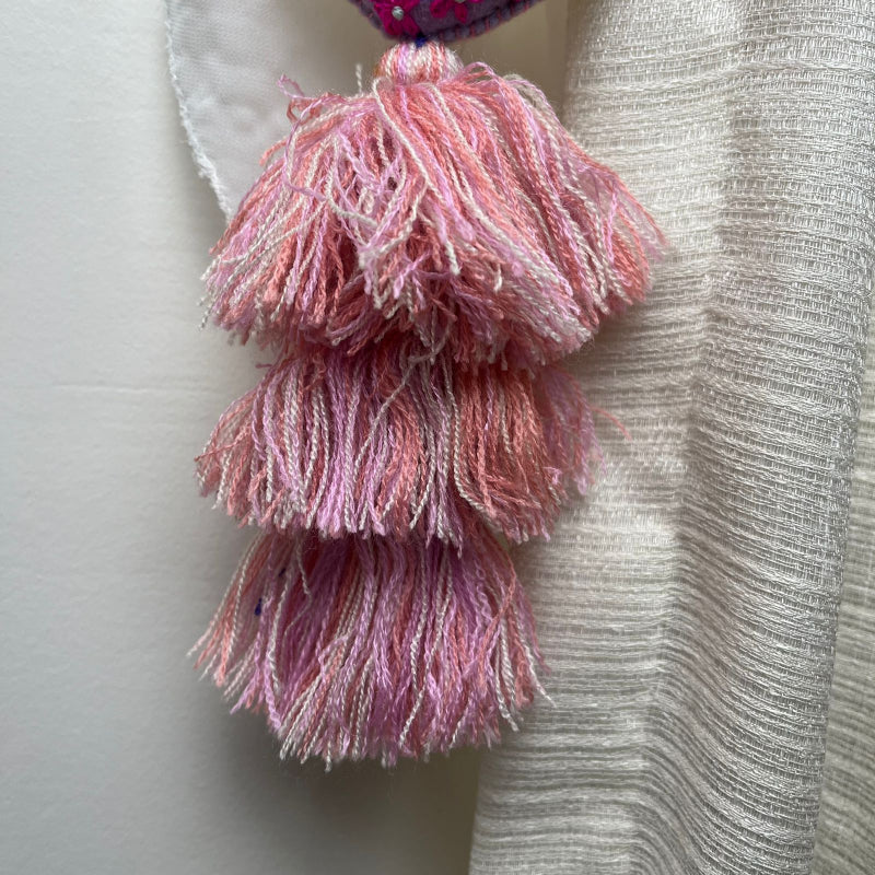 Handmade lavender embroidered heart tassel with colorful floral embroidery and pink yarn fringe on curtain
