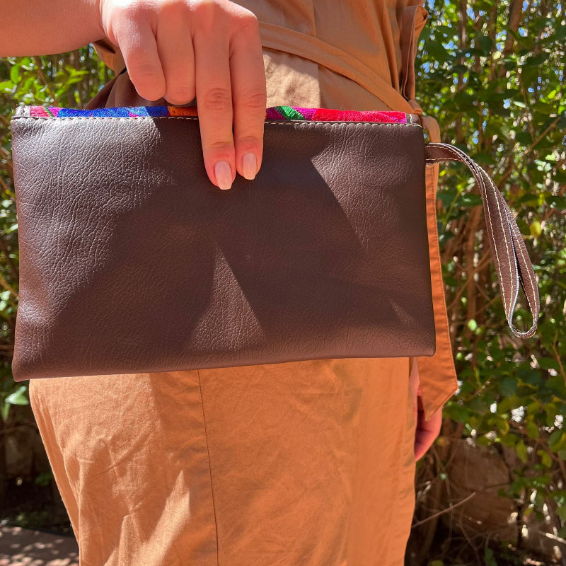 Woman wearing a brown leather shoulder bag with bold red floral embroidered flap outdoors