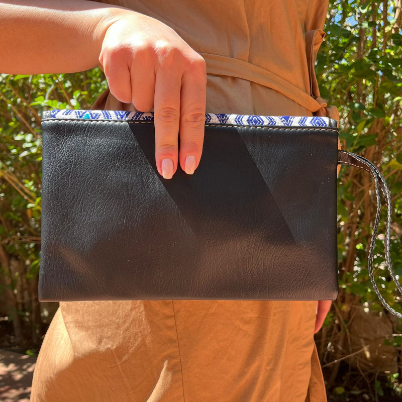 Woman wearing a black leather shoulder bag with blue patterned embroidered flap outdoors