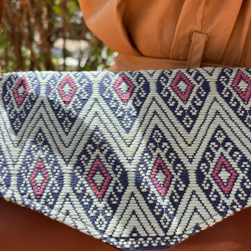 Woman wearing a brown leather crossbody bag with black and grey geometric woven flap outdoors