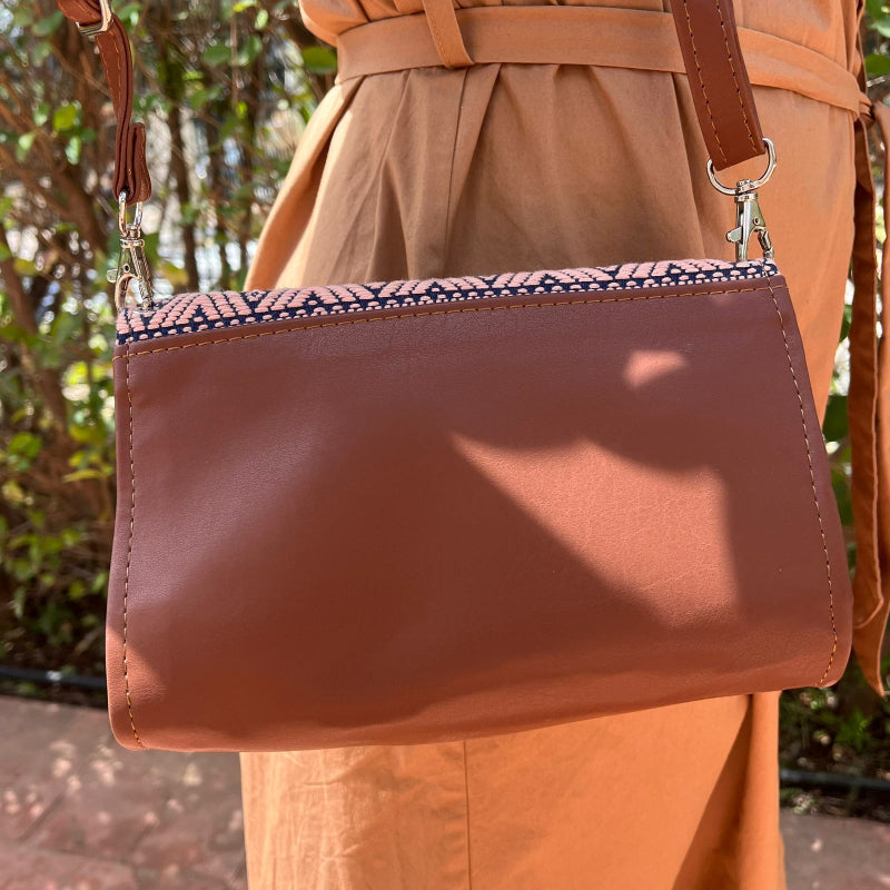 Woman wearing a brown leather crossbody bag with beige and navy geometric woven flap outdoors